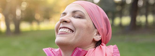 happy mature woman smiling with a pink scarf, symbol against breast cancer