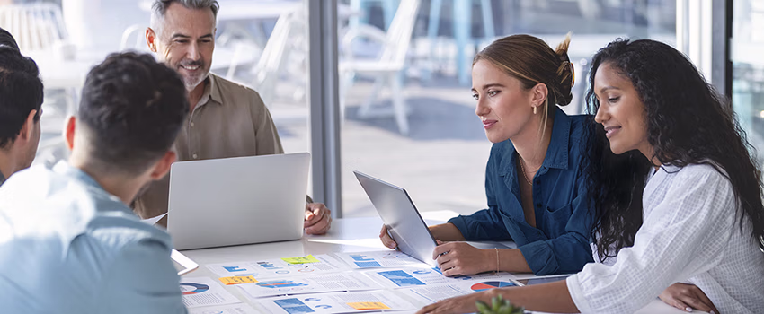 Multi racial diverse group of people working with Paperwork on a board room table at a business brainstorm, presentation or seminar