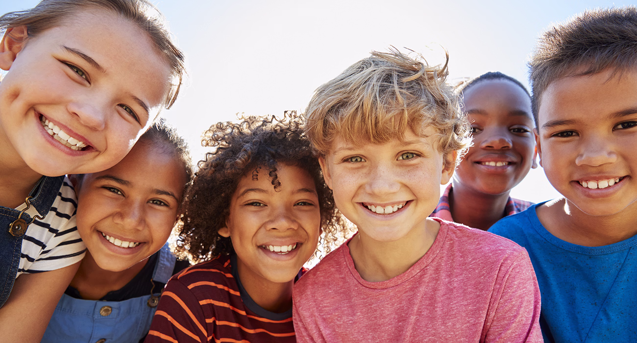 Close up of pre-teen friends in a park smiling to camera