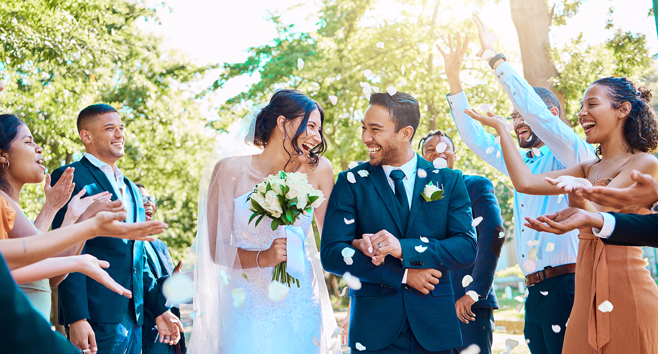 Wedding guests throwing rose petals confetti tradition over bride and groom on their special day