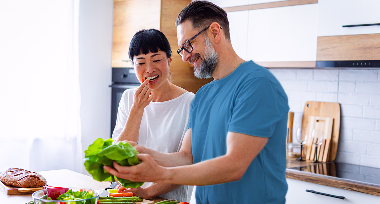 Cheerful couple preparing fresh vegetables in a modern kitchen